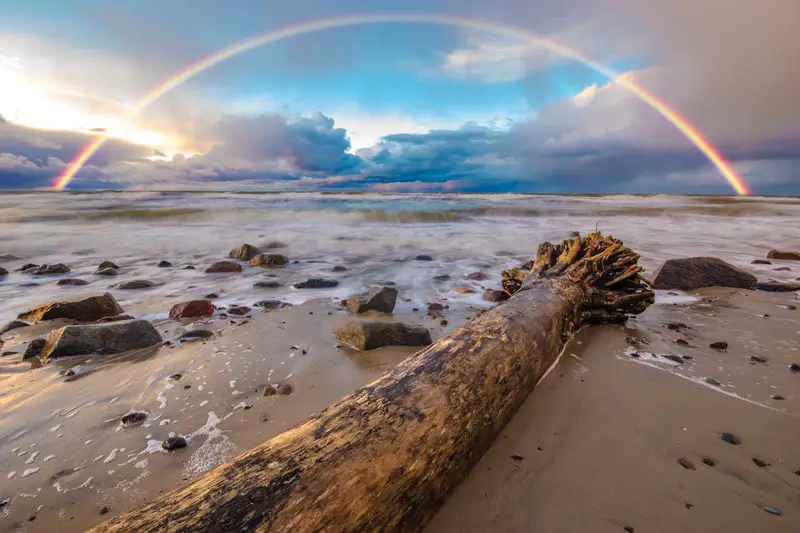 Storm Clouds Over The Sea Beach and a Rainbow