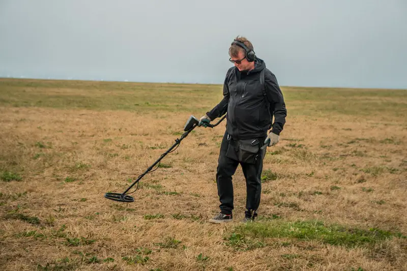 Man metal detecting in a field.