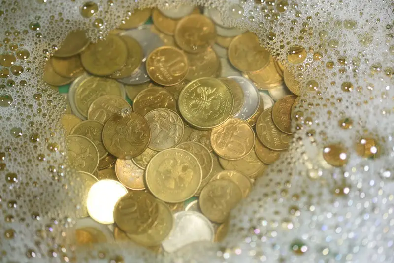 large pile of old, dirty coins soaking in water and soap