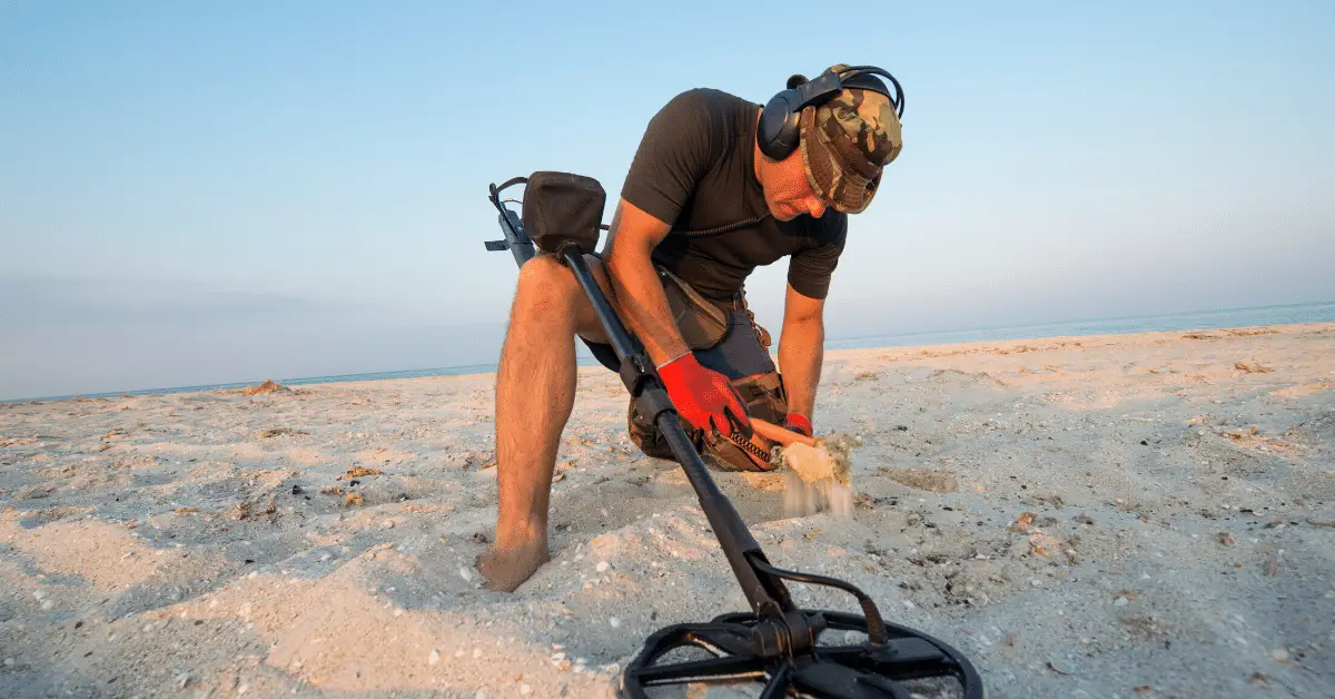 Man metal detecting on the beach.