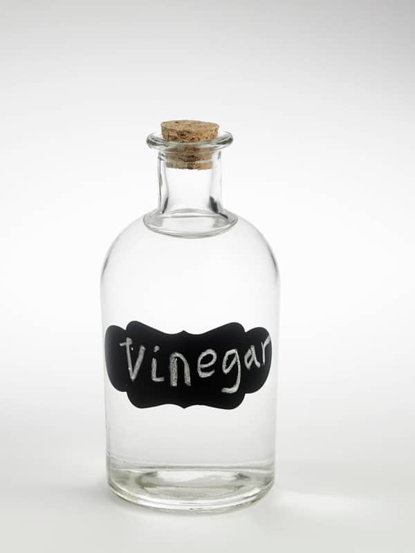 Jar of white vinegar with cork top.