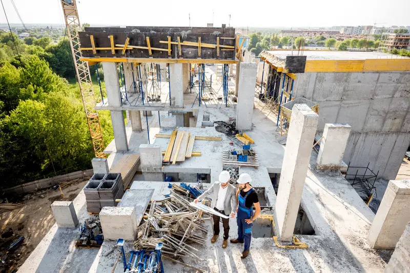 Top view on the construction site of residential buildings during the construction process with two workers standing with drawings