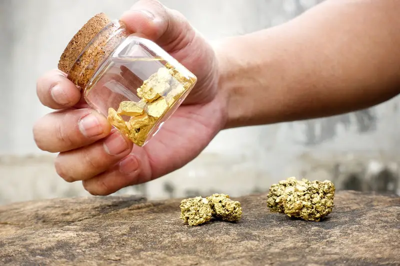 Human hands are swinging bottles that contain pure gold minerals found in mines.