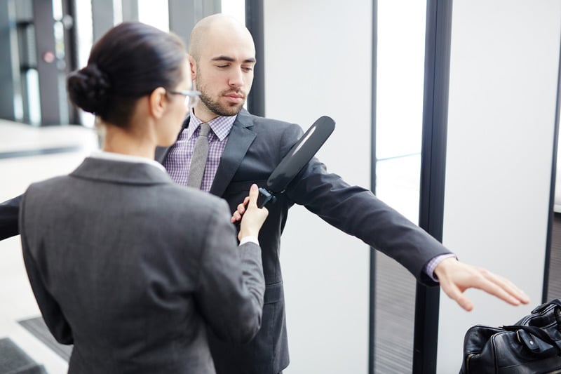 Airport security checking one of passengers with metal detector on entrance