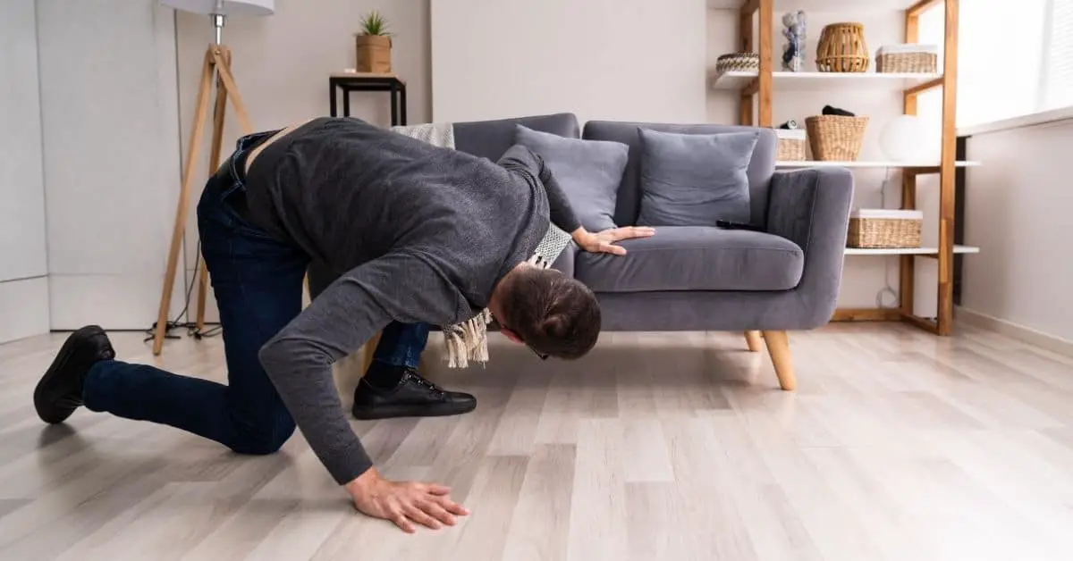 Man looking under a couch for his lost keys