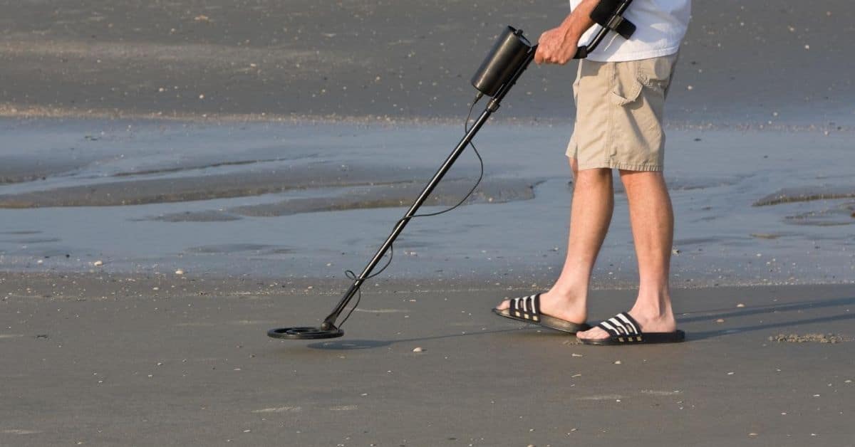 Man metal detecting on the beach.