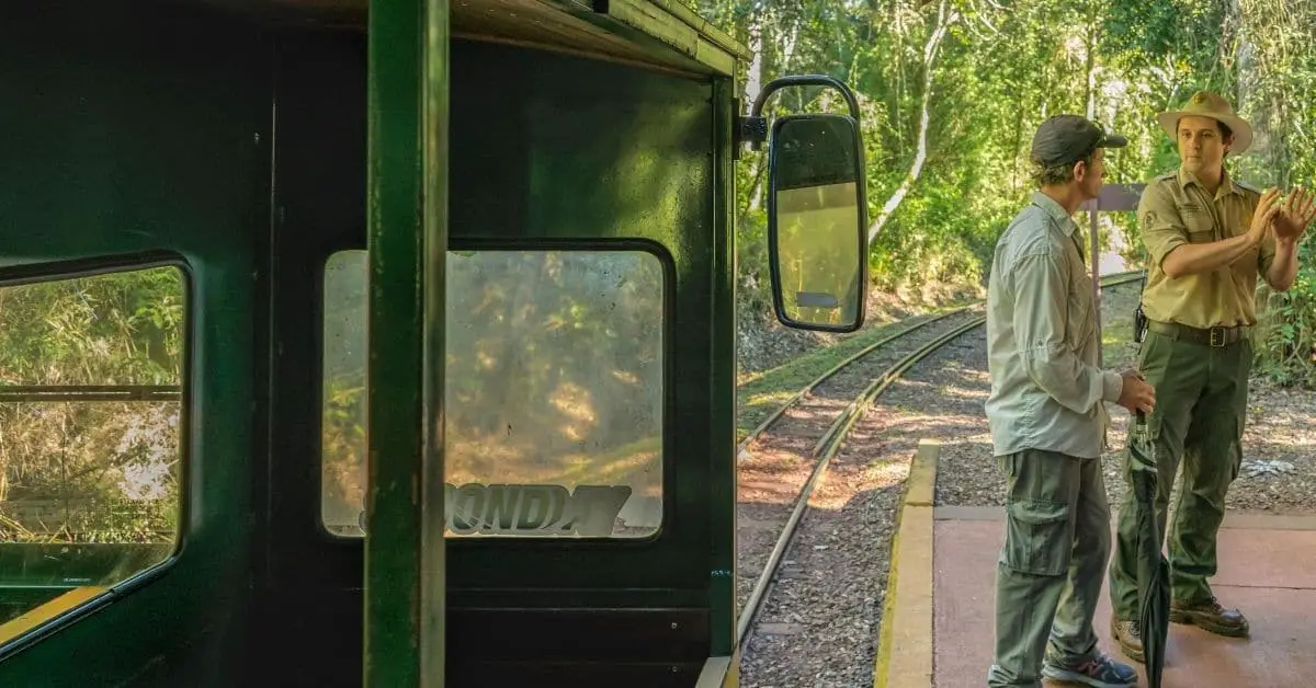 Two men standing by a train in the woods