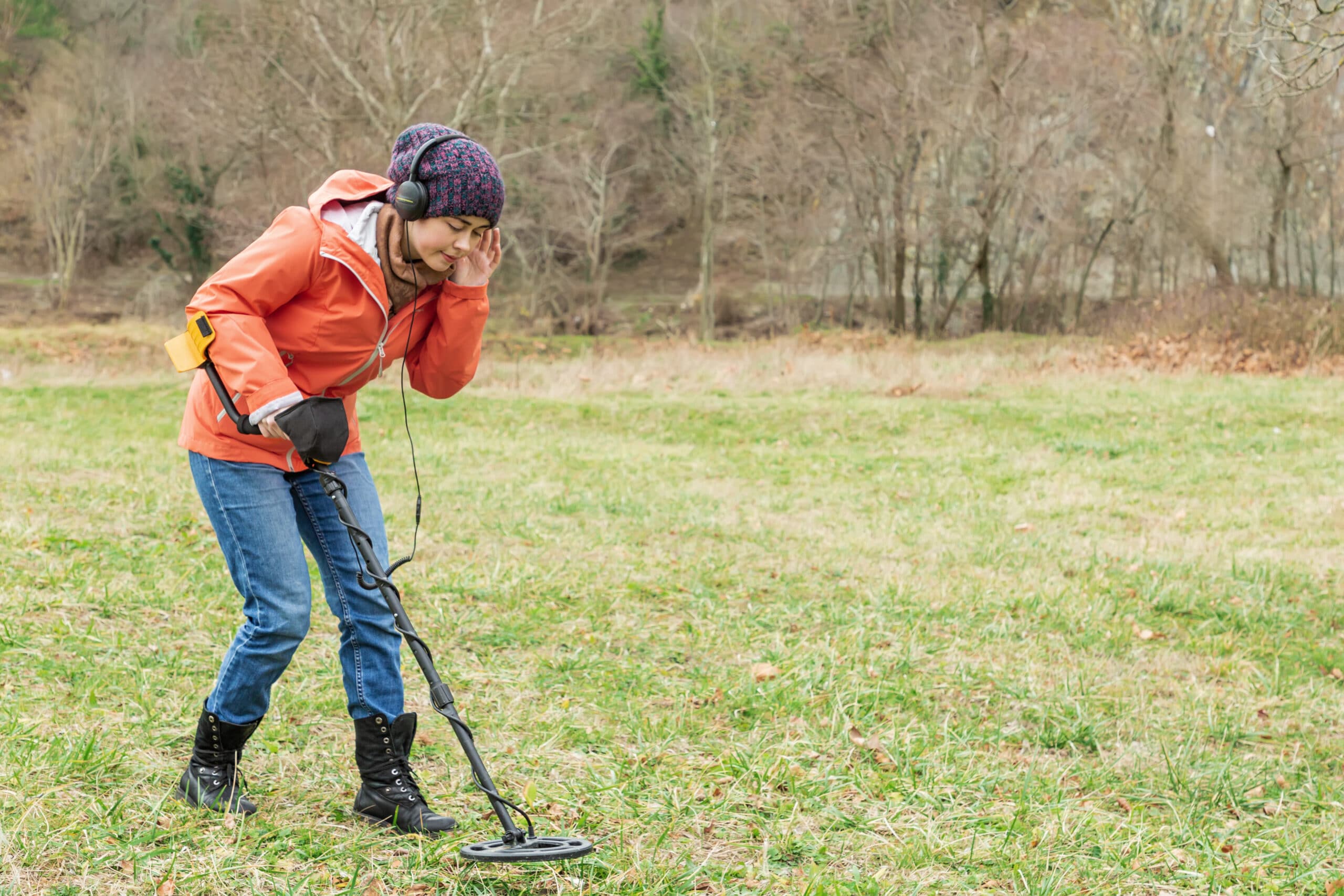 Woman wearing headphones while metal detecting.