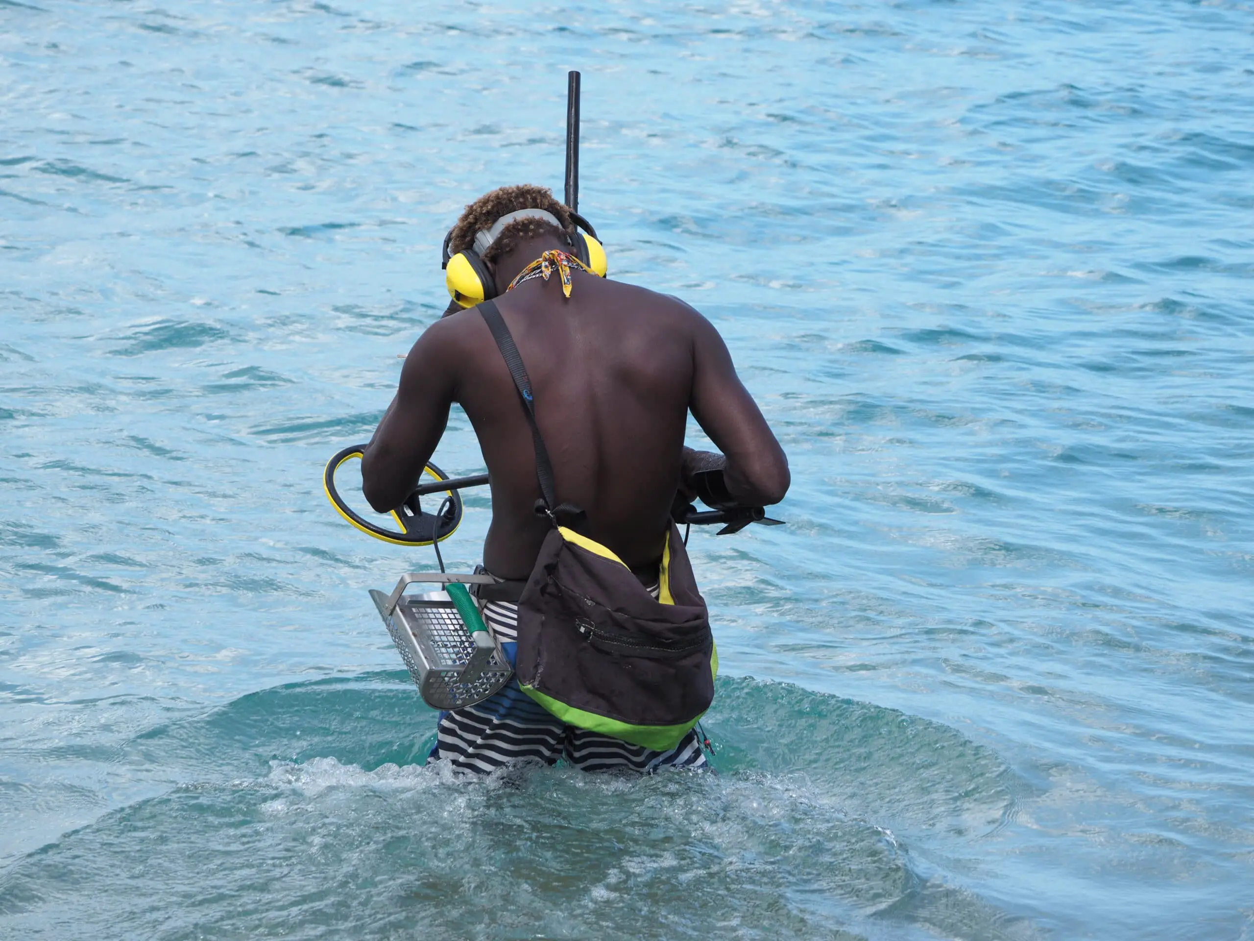 A man searches the ocean for jewels with a metal detector.