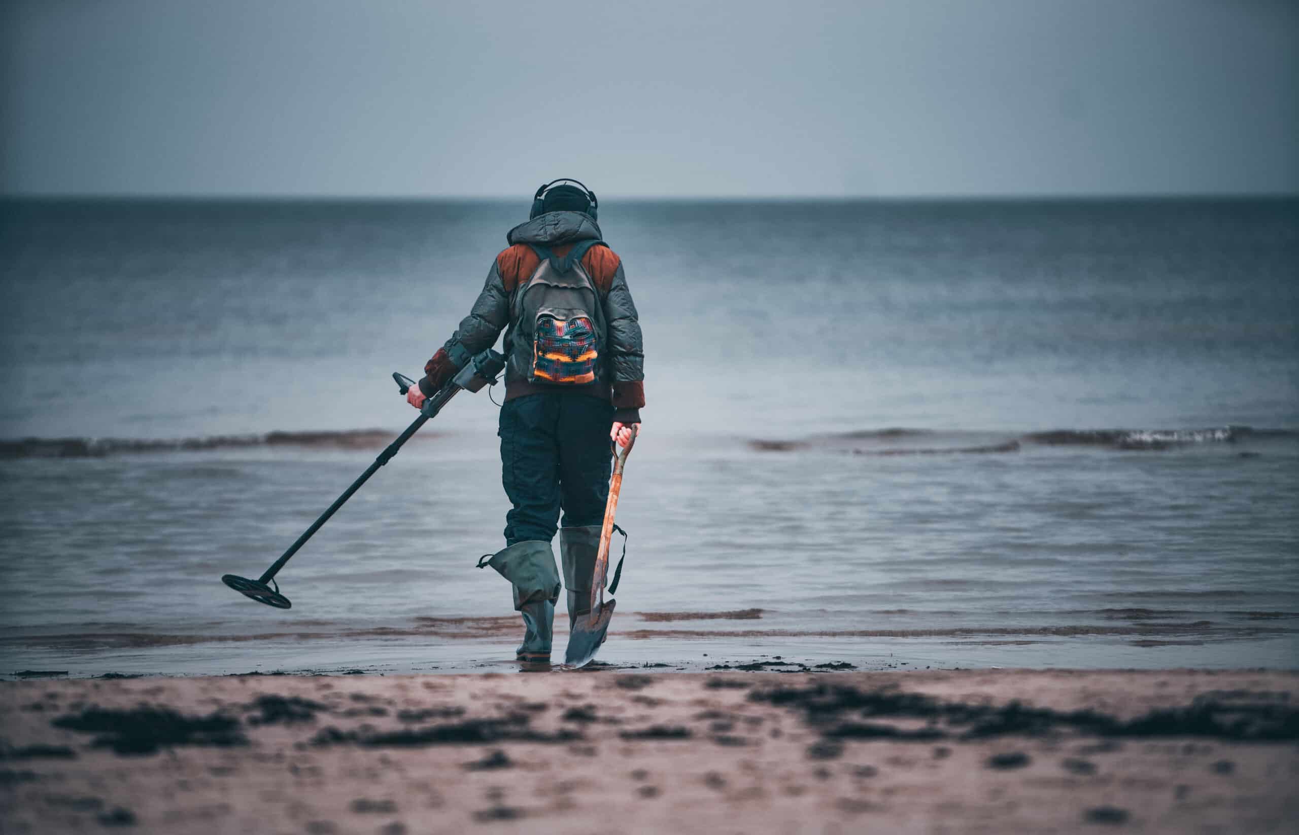 Man with a metal detector on a sea sandy beach